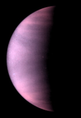 Image of clouds on the planet Venus. The planet is shown half in darkness, and the clouds appear in this ultraviolet-light image as a hazy, pink-purple colour